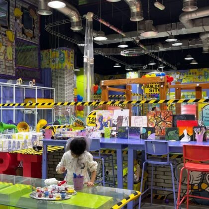 A-girl-in-a-kids-play-area-panting-and-behind-her-are-kids'-games.