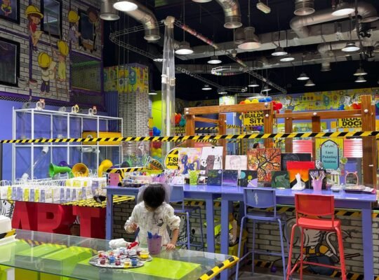 A-girl-in-a-kids-play-area-panting-and-behind-her-are-kids'-games.