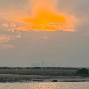 A stunning sunset view from Al Bahya Hidden Beach, with the Abu Dhabi skyline visible in the background, creating a peaceful and scenic coastal atmosphere.