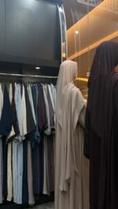 sharqiaa Abaya store in Abu Dhabi showcasing neutral-colored abayas and elegant fabric designs on display.